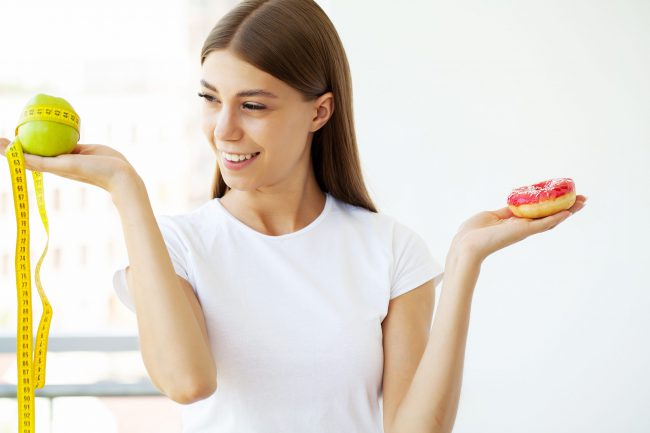 cómo adelgazar sin pasar hambre – chica entre donut y manzana cómo adelgazar sin pasar hambre - chica entre donut y manzana